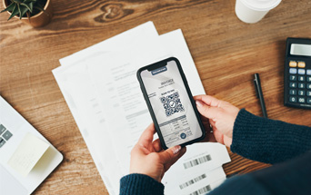 Woman scanning QR code of invoice placed on a table using mobile